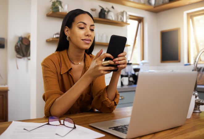 a woman at her desk smiling at her smartphone