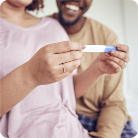 couple smiling at a positive pregnancy test