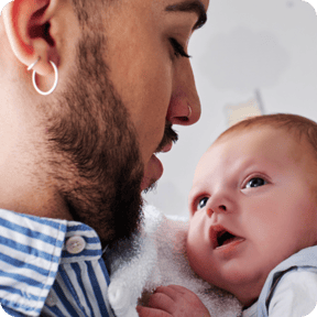 dad holding smiling baby boy against his shoulder