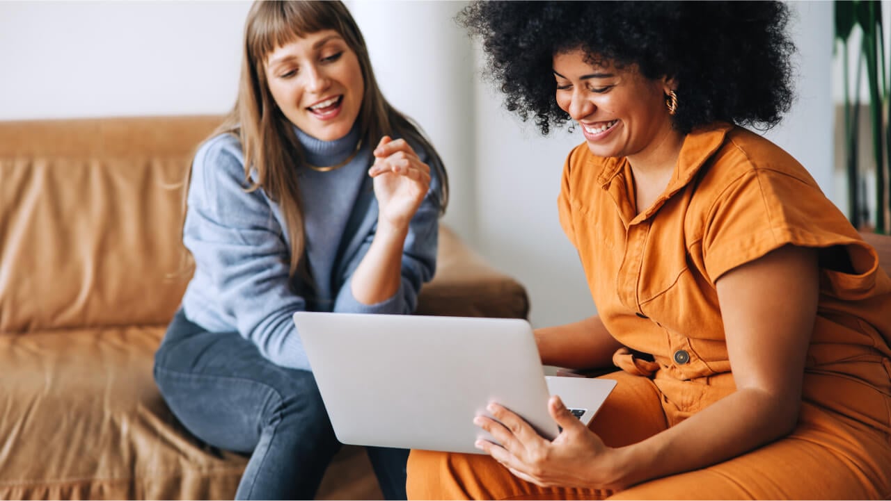 Two woman sitting on sofas with a laptop-1