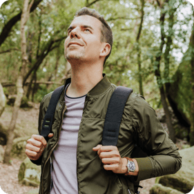 a man smiling as he walks through the woods